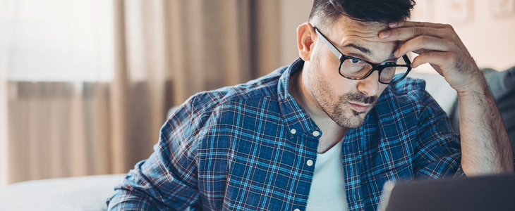 man with glasses holding his head worried about bankruptcy