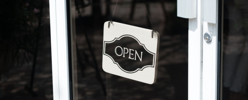 black and white open for business sign hanging on a businesses front door