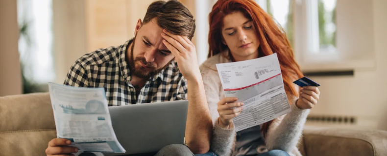 Worried couple feeling frustrated while have to pay their bills over Internet.